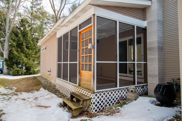 view of snow covered exterior with a sunroom