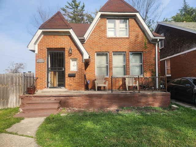 view of front of property with fence, a front lawn, and brick siding