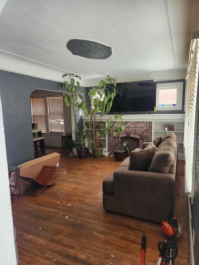 living area featuring a brick fireplace and wood finished floors