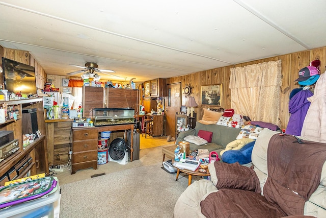 carpeted living room featuring a ceiling fan and wood walls