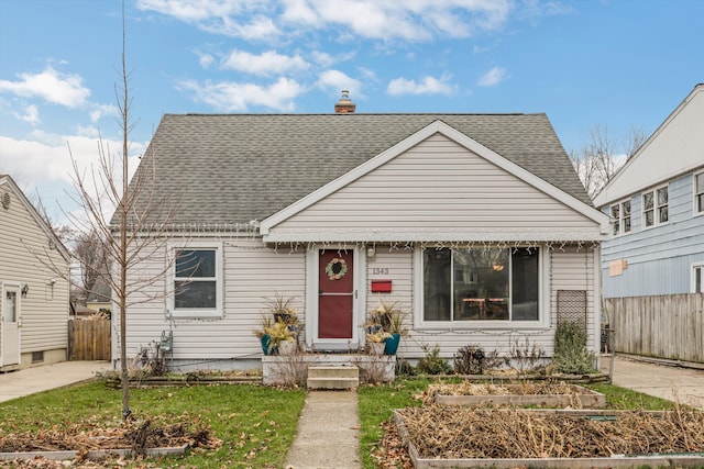 bungalow-style house featuring a shingled roof, a garden, fence, and a chimney