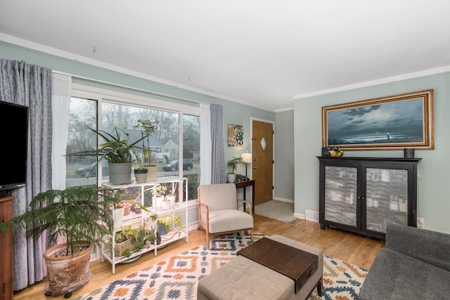 living room featuring ornamental molding, wood finished floors, visible vents, and baseboards