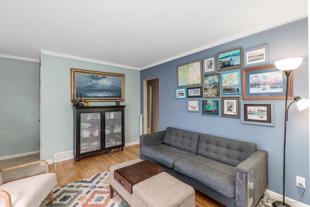 living room with crown molding, wood finished floors, visible vents, and baseboards