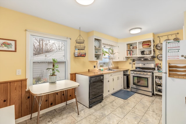 kitchen with black dishwasher, open shelves, gas stove, freestanding refrigerator, and a sink