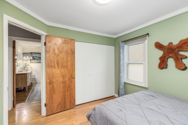 bedroom featuring ornamental molding, a closet, and wood finished floors