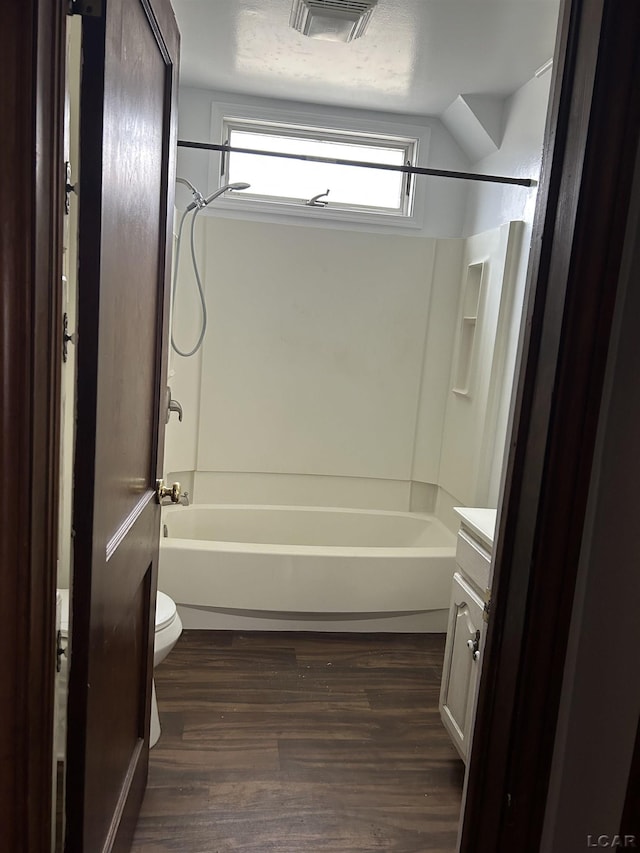 bathroom with visible vents, toilet, vanity, wood finished floors, and shower / bathtub combination