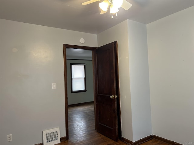 hall with visible vents, dark wood finished floors, and baseboards