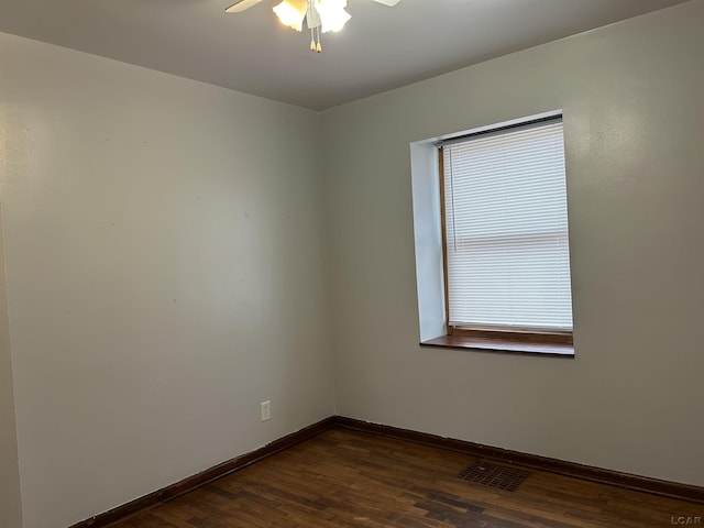 unfurnished room featuring dark wood-type flooring, visible vents, baseboards, and a ceiling fan