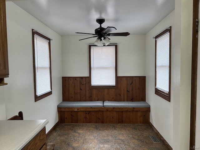 interior space with visible vents, stone finish flooring, a wainscoted wall, and a wealth of natural light