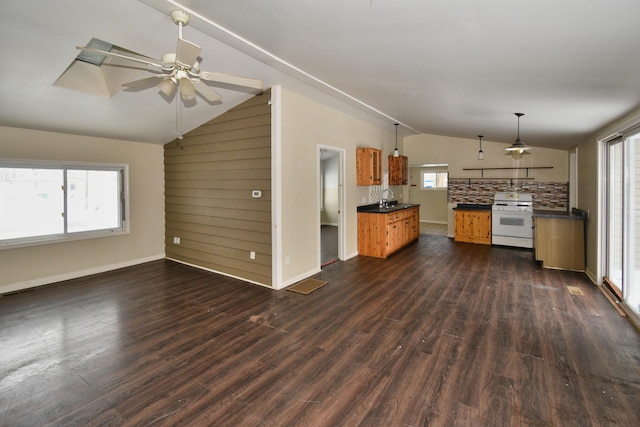 kitchen with dark wood-type flooring, dark countertops, white range with gas stovetop, and lofted ceiling