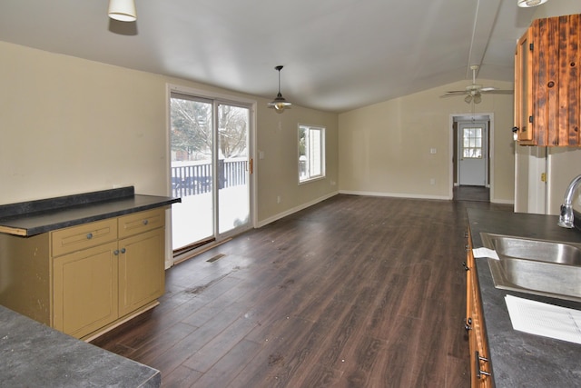 kitchen featuring baseboards, dark countertops, dark wood-style floors, vaulted ceiling, and a sink