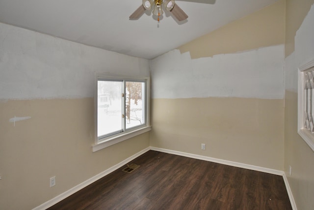 spare room with lofted ceiling, baseboards, visible vents, and dark wood-style flooring