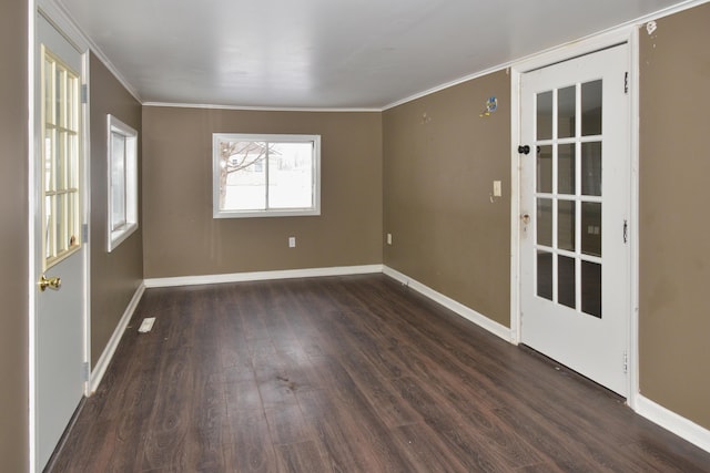 spare room featuring baseboards, dark wood finished floors, and crown molding