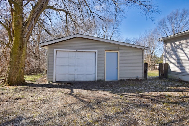 detached garage featuring dirt driveway and fence