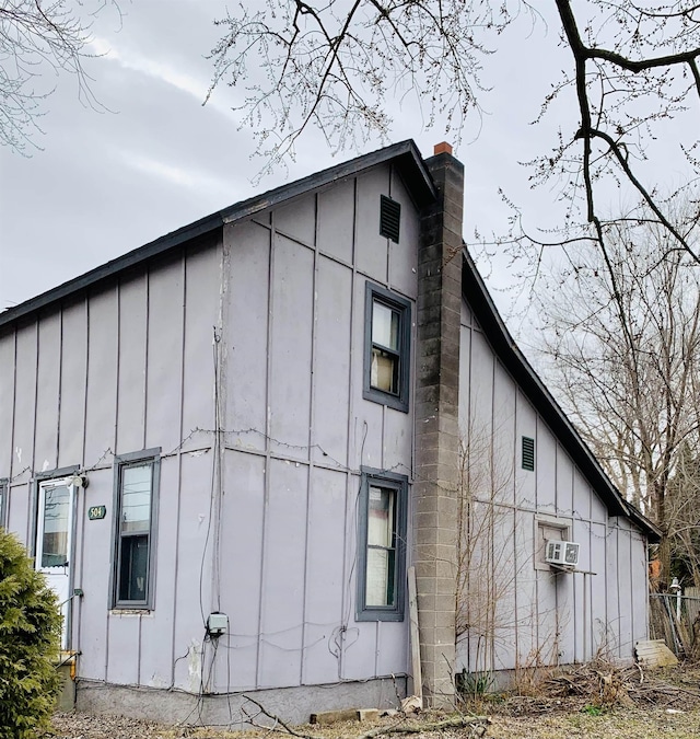 view of side of home featuring board and batten siding and a chimney