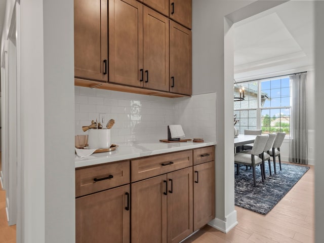 kitchen with light countertops, backsplash, light wood-style flooring, and brown cabinets