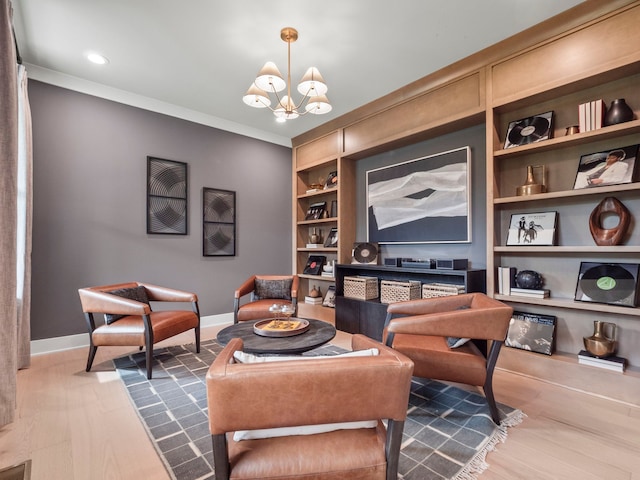 living area with built in shelves, baseboards, a notable chandelier, and ornamental molding