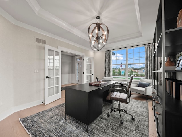 office area featuring french doors, light wood finished floors, a raised ceiling, visible vents, and ornamental molding