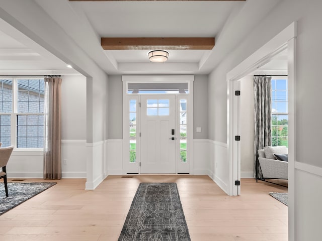 foyer entrance with light wood-type flooring, a wealth of natural light, and wainscoting