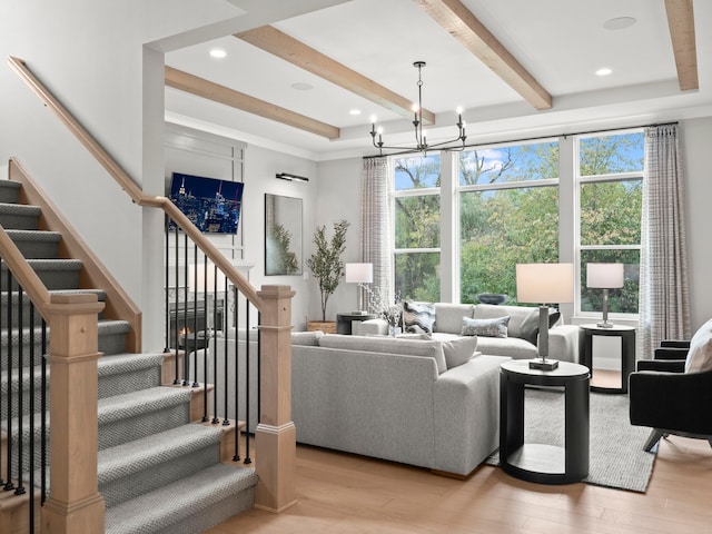 living area with light wood-style flooring, stairs, a chandelier, and beamed ceiling