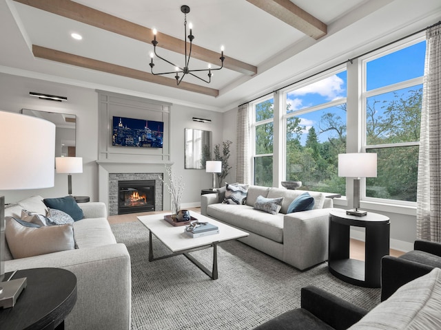 living area with a stone fireplace, a raised ceiling, beam ceiling, and a healthy amount of sunlight