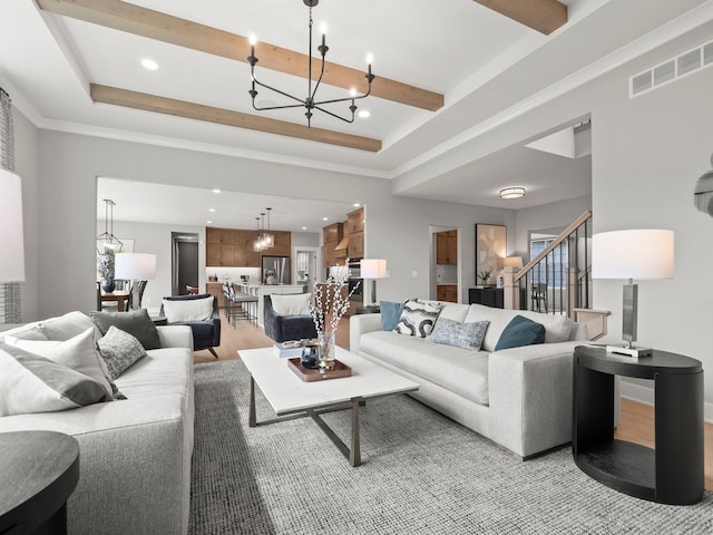 living room featuring an inviting chandelier, visible vents, a raised ceiling, and beamed ceiling