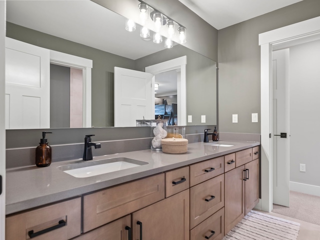 bathroom with double vanity, baseboards, and a sink