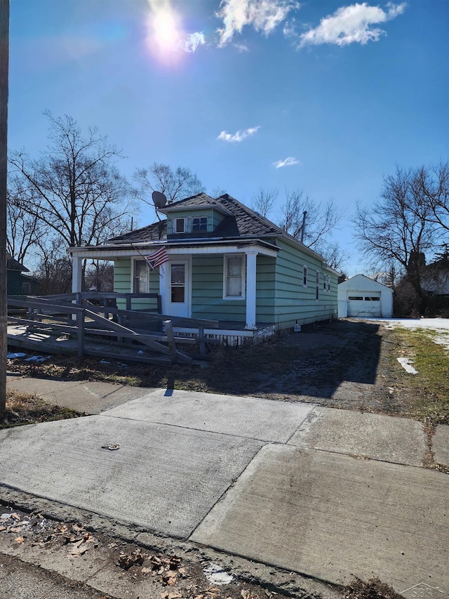 view of front of property with driveway, covered porch, a detached garage, and an outdoor structure