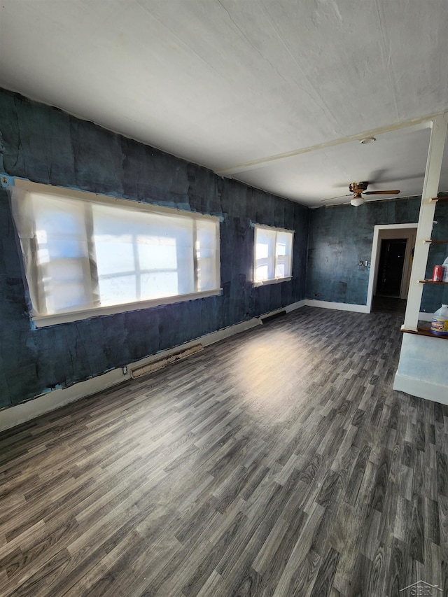 unfurnished living room with ceiling fan, baseboards, and dark wood finished floors