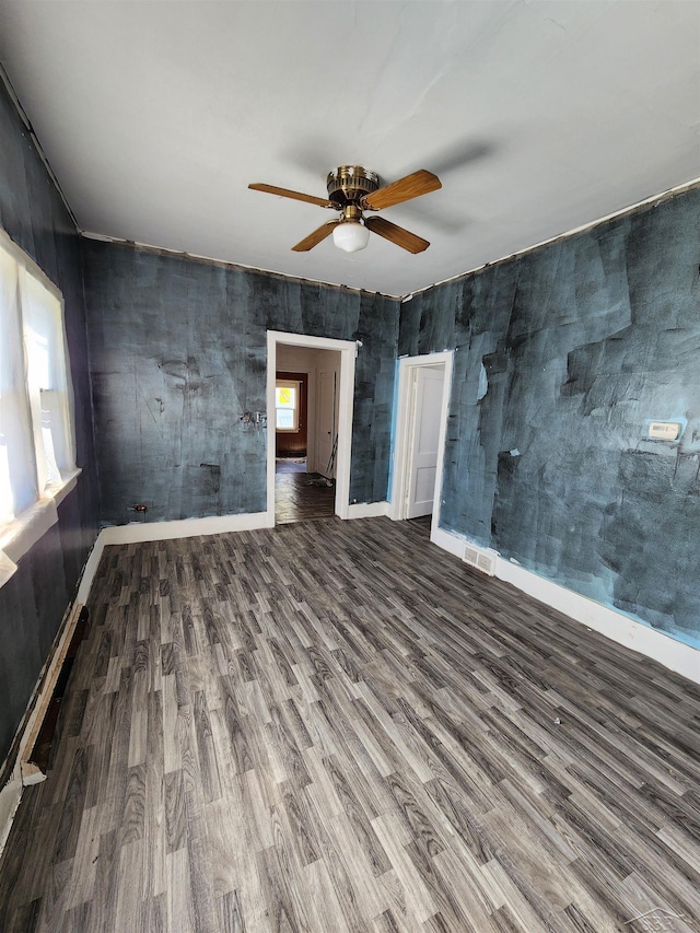 unfurnished room with a ceiling fan, wood finished floors, visible vents, and baseboards