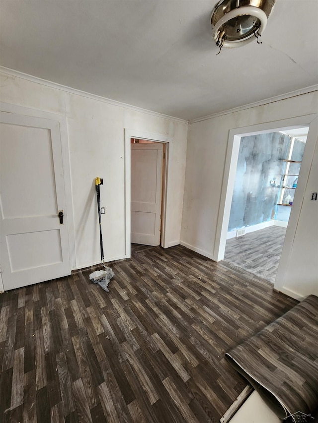 empty room featuring dark wood-style floors, baseboards, and ornamental molding