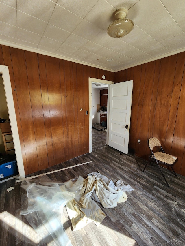 unfurnished bedroom featuring wooden walls, dark wood finished floors, and a closet