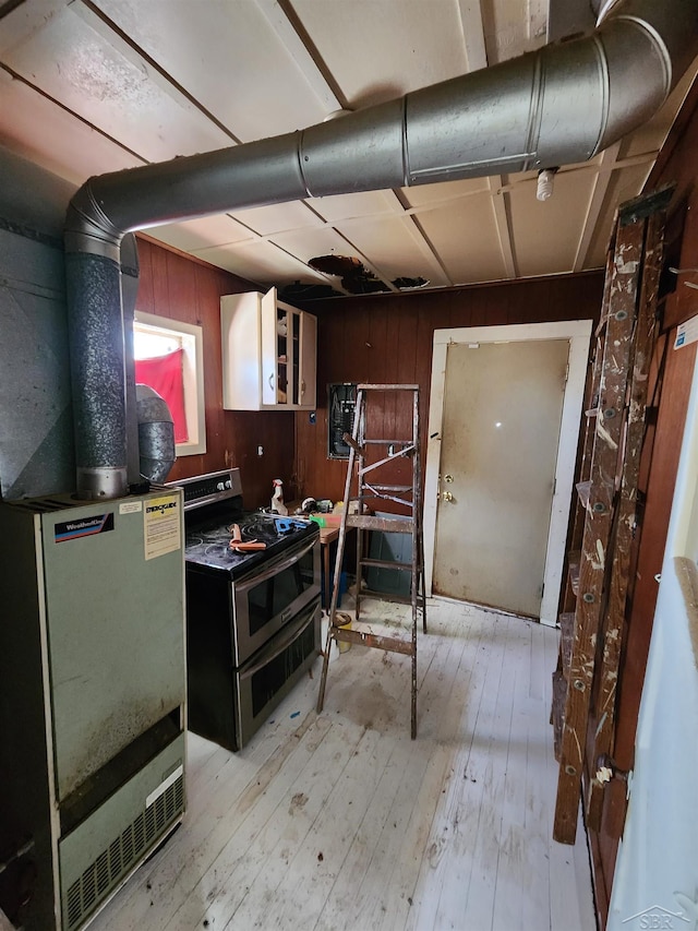 kitchen with light wood finished floors, fridge, wooden walls, and range with two ovens