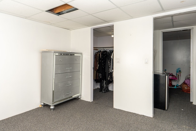 unfurnished bedroom with a closet, carpet, a walk in closet, and a paneled ceiling