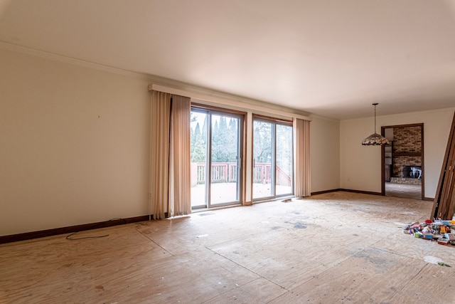 spare room featuring crown molding, a brick fireplace, and baseboards