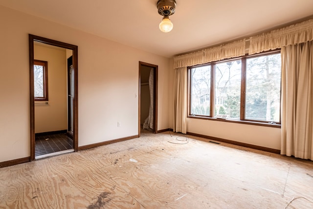 unfurnished bedroom featuring ensuite bath and baseboards