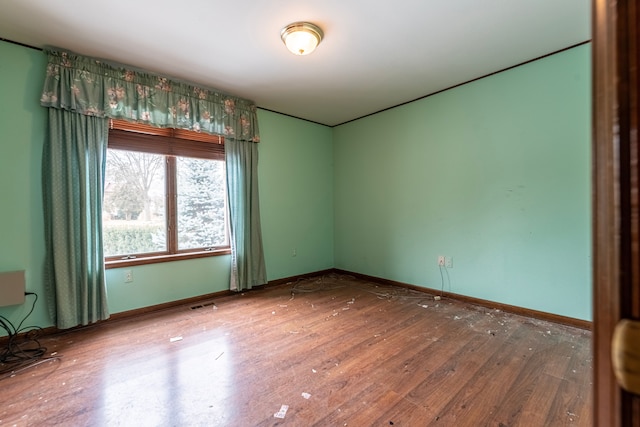 spare room featuring baseboards, visible vents, and hardwood / wood-style floors