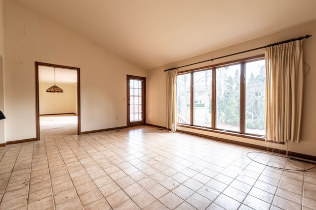 spare room featuring light tile patterned flooring, vaulted ceiling, and baseboards