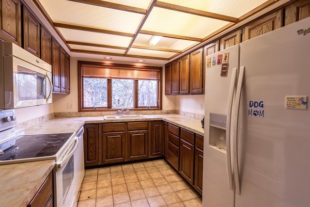 kitchen featuring light countertops, white appliances, and a sink