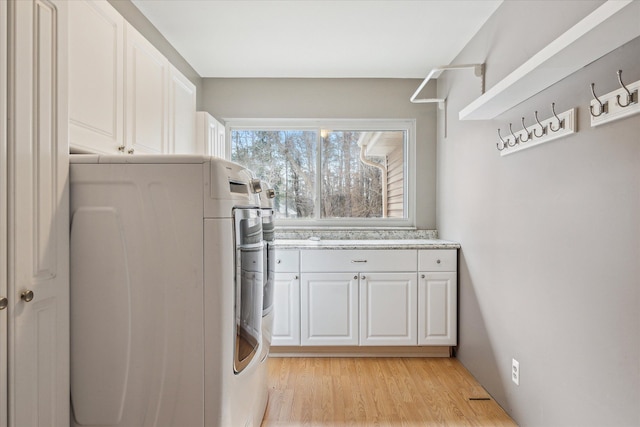 laundry room with washer / clothes dryer, cabinet space, and light wood finished floors