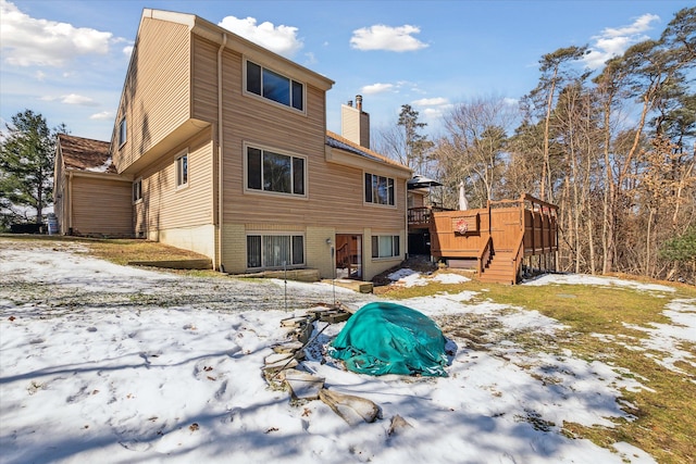 snow covered property featuring stairs, a chimney, and a wooden deck