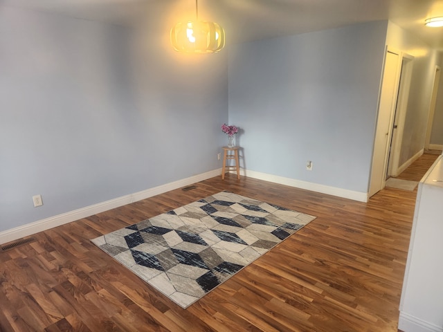 spare room with visible vents, baseboards, and wood finished floors