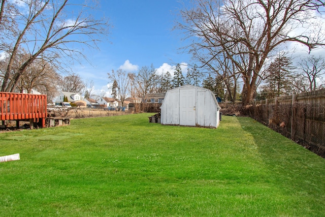 view of yard with an outdoor structure, a storage unit, a fenced backyard, and a wooden deck