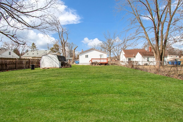 view of yard with a fenced backyard, an outdoor structure, a storage shed, and a deck