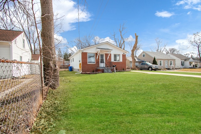 view of front of house featuring brick siding, a front lawn, and fence