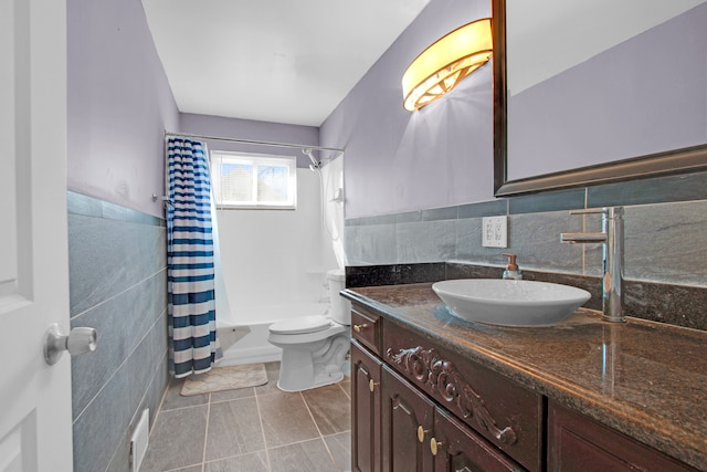 full bath with vanity, shower / bathtub combination with curtain, a wainscoted wall, tile walls, and toilet
