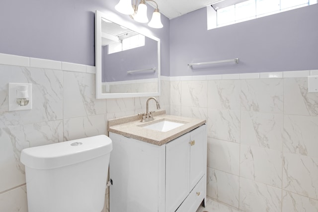 bathroom featuring vanity, tile walls, toilet, and marble finish floor