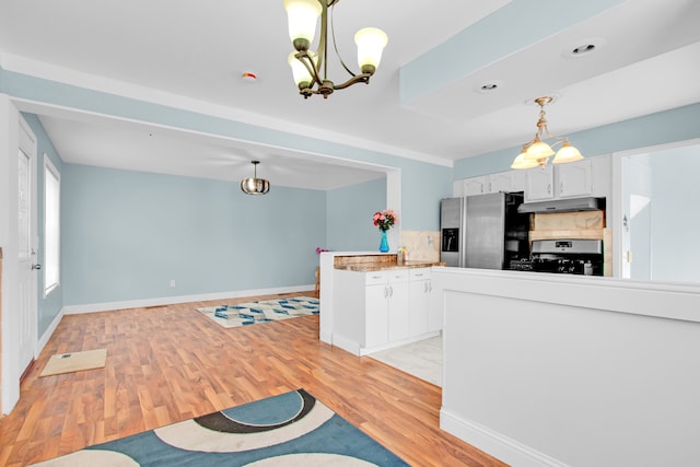kitchen with range with gas stovetop, light wood-style flooring, stainless steel refrigerator with ice dispenser, under cabinet range hood, and a notable chandelier