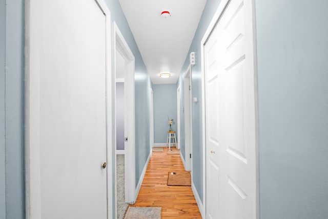 hallway with light wood finished floors and baseboards