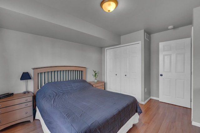 bedroom featuring visible vents, a closet, baseboards, and wood finished floors